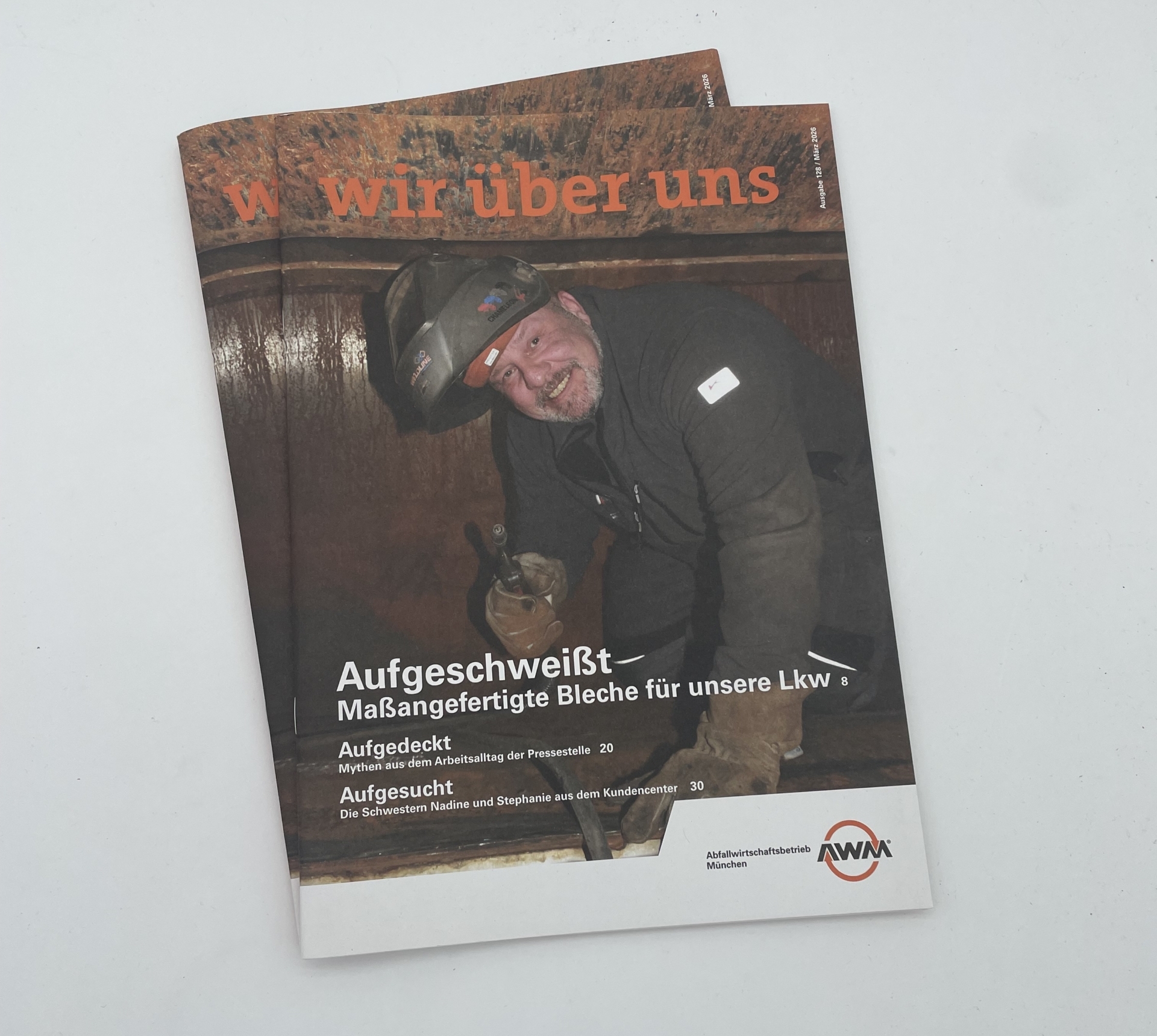 Cover des Mitarbeitermagazins „Wir über uns“ Print-Ausgabe 128 März 2026 des Abfallwirtschaftsbetriebs München mit Mitarbeiter bei Schweißarbeiten